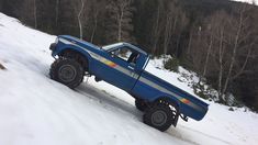 a blue truck driving down a snow covered slope