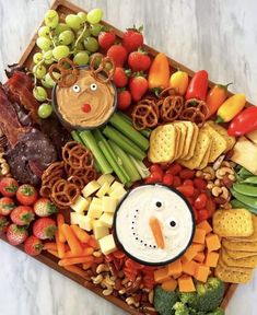 a platter filled with fruit, crackers, cheeses, and vegetables as well as an image of a snowman