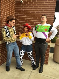 three people dressed up as toy story characters standing in front of a brick wall and posing for the camera