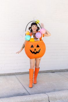 a woman dressed as a pumpkin with balloons on her head and an orange rubber boot