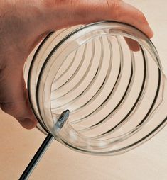 a person is holding a glass object with a metal wire attached to the top of it