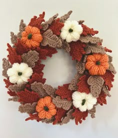 a crocheted wreath with white and orange flowers