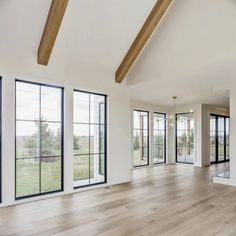 an empty living room with wood floors and large windows