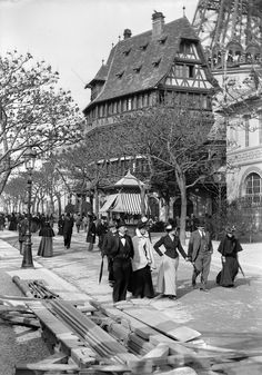 an old black and white photo of people walking down the street in front of a building