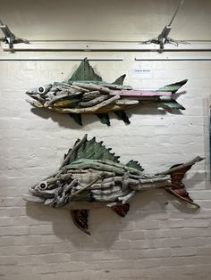 two fish made out of driftwood are hanging on the wall