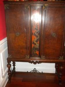 an old wooden armoire sitting on top of a hard wood floor next to a red wall