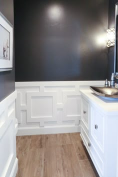 a bathroom with wood flooring and white walls, painted in dark gray paint on the wall