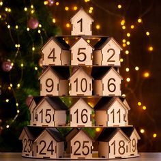 a christmas tree made out of wooden houses with numbers on them and lights in the background