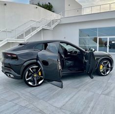 a black sports car parked in front of a white building with stairs leading up to it