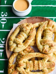 pretzels on a wooden plate next to a cup of coffee and football field