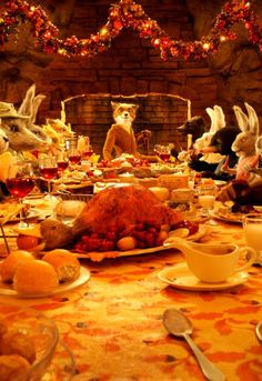 a table filled with food and stuffed animals sitting on it's sides in front of a fireplace