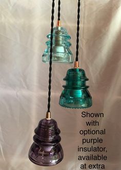 three glass bells hanging from black cords with the words shown below them in english and spanish