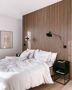 a white bed sitting in a bedroom next to a wooden wall