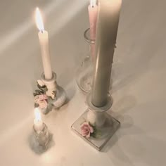 two candles are sitting next to each other on a white table top with pink flowers