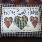 a pillow that says home sweet home with two hearts on the front and one heart in the back