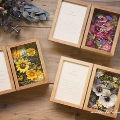 four wooden boxes filled with flowers on top of a wooden table next to other items