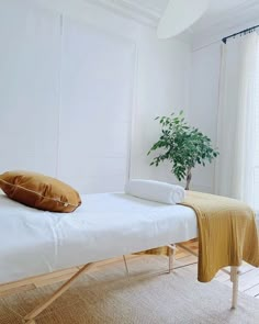 a white bed sitting in a bedroom next to a plant on top of a table