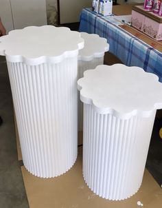 two large white vases sitting next to each other on top of a table covered in paper