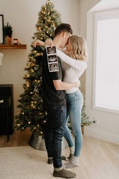 a man and woman kissing in front of a christmas tree