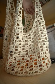 a crocheted bag sitting on top of a table next to a person's hand