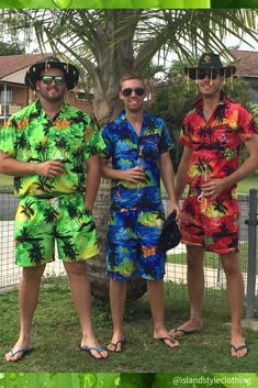 three men standing next to each other near a tree wearing colorful shirts and shorts with palm trees in the background