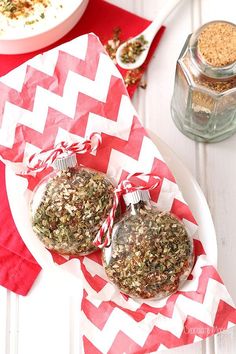 two christmas ornaments on a plate with red and white napkins