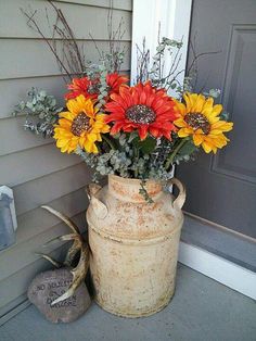 a vase filled with lots of flowers sitting on the side of a house next to a door