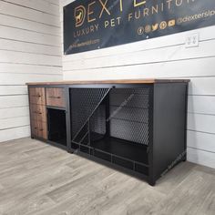 a large black dog crate sitting on top of a hard wood floor next to a white wall