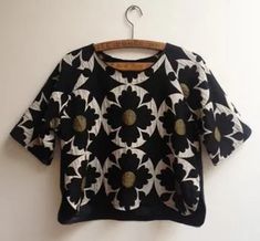 a black and white flower sweater hanging on a wall next to a wooden hanger