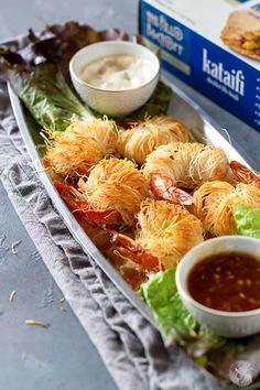 a platter with shrimp, lettuce and sauce on it next to a carton of yogurt