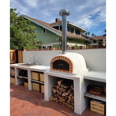 an outdoor pizza oven built into the side of a house with lots of wood stacked in it