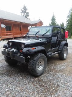 a black jeep parked in front of a cabin