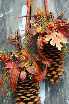 two pine cones decorated with autumn leaves and berries are hanging on a door handle,