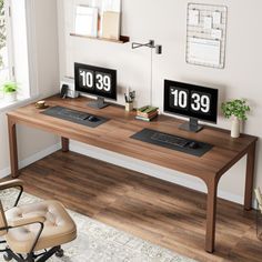 two computer monitors sitting on top of a wooden desk next to a chair and window