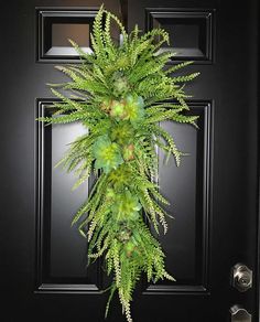 a black door with a green plant hanging on it