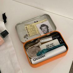 an orange and white tin with personal items in it sitting on a table next to other items