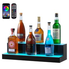 there are many different types of liquor on the shelf with remotes next to it