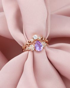 a ring with an amethorate surrounded by diamonds on a pink satin background