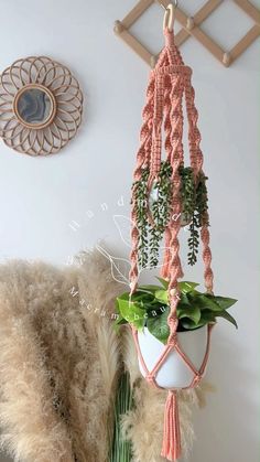 a potted plant hanging from a wooden hook on a wall next to a white vase with green plants in it