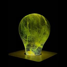 a green vase sitting on top of a wooden table next to a black wall and floor