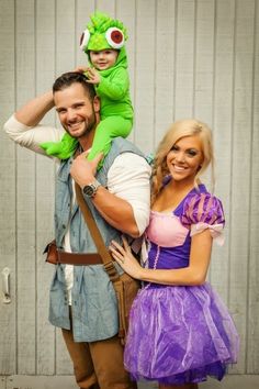 a man and woman dressed up as princesses with a child on their shoulders, standing next to each other