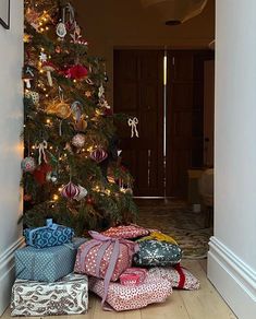 a christmas tree with presents under it in front of a door way that leads to a hallway