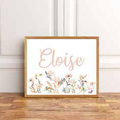 a framed sign with the word elsie painted in pink and orange flowers on it, against a white wall