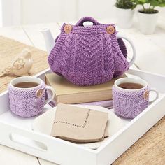 a tray with two cups and a teapot in it on top of a table