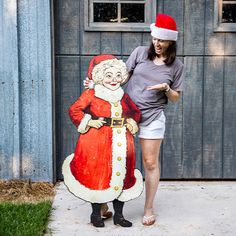 a woman standing next to a large wooden santa clause