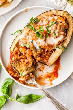 an eggplant stuffed with meat and cheese on a white plate next to a fork