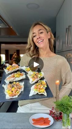 a woman holding a tray with sushi on it in front of a kitchen counter