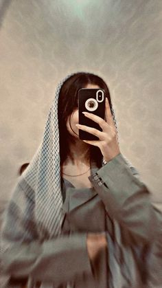 a woman taking a selfie with her cell phone in front of her face and wearing a veil