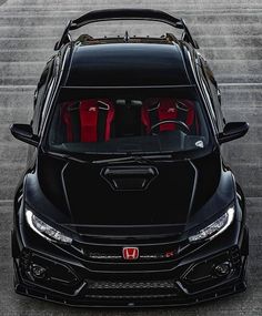 the front end of a black car with red seats in it's trunk and hood