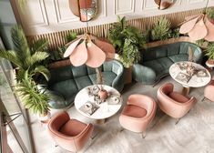 an overhead view of a restaurant with pink and green chairs, palm trees, and round tables